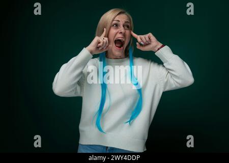 Une femme aux longs cheveux bleus saisissants le drape sur ses yeux, obscurcissant partiellement son visage. Les serrures bleues éclatantes contrastent nettement avec son beau c Banque D'Images