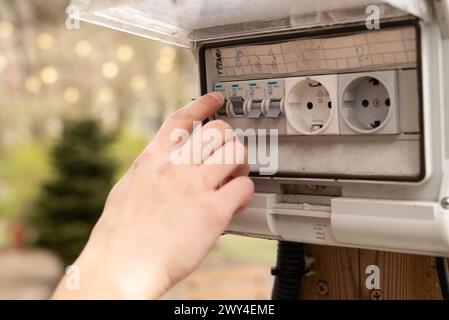 Doigt de l'homme vérifiant une électricité dans la boîte à fusibles à l'extérieur. Bloc de prises avec un interrupteur au jardin. Photo de haute qualité Banque D'Images