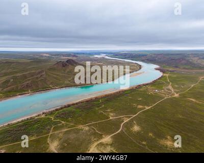 Une vue aérienne de la rivière Ili au début du printemps par une journée nuageuse. La rivière Ili coule à travers un paysage pittoresque parmi des collines verdoyantes. Kazakhstan Banque D'Images