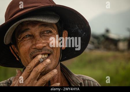 Homme vietnamien fumant une cigarette et prenant une pause de son travail sur le terrain. Portrait d'un fermier vietnamien dans le champ. Nha Trang Vietnam. Avr Banque D'Images