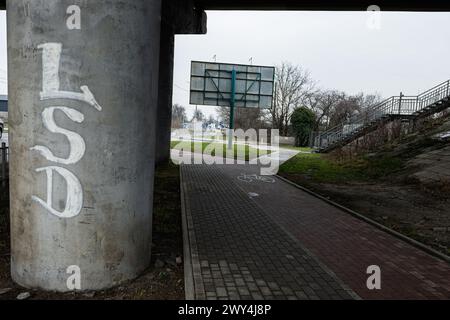 Lutsk, Ukraine - mars 2024 : texte graffiti LSD sur une colonne de béton à côté d'une piste cyclable pavée menant sous un pont avec un panneau d'affichage vide et St Banque D'Images