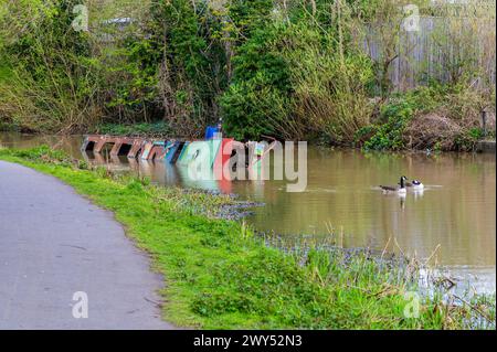 Une vue vers une épave de bateau sur le canal Grand Union canal à Aylestone Meadows, Leicester, Royaume-Uni au printemps Banque D'Images