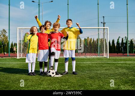 Un groupe de jeunes enfants, plein d’énergie et d’enthousiasme, se tient triomphalement au sommet d’un terrain de soccer, célébrant leur travail d’équipe et leur victoire. Banque D'Images