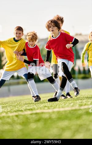 Un groupe de jeunes enfants sont immergés dans un jeu animé de football, courir, frapper et passer le ballon avec enthousiasme et travail d'équipe sur un fie herbeux Banque D'Images