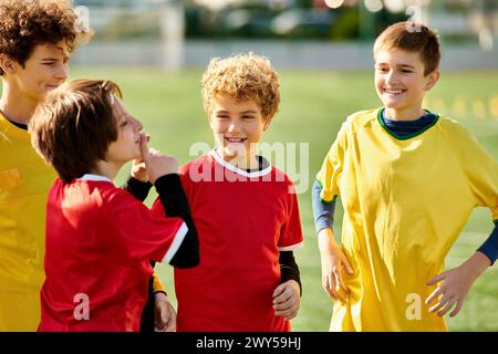 Un groupe de jeunes garçons énergiques en uniforme de football se tiennent ensemble sur le terrain de football vert vibrant, prêts pour un match. Leurs visages montrent de la détermination Banque D'Images