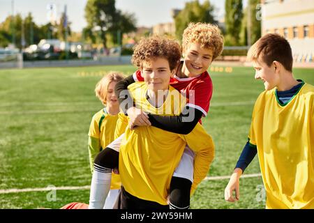 Un groupe de jeunes garçons se tient triomphalement au sommet d'un terrain de football, célébrant leur victoire avec des sourires et des cinq hauts après un match compétitif. Banque D'Images