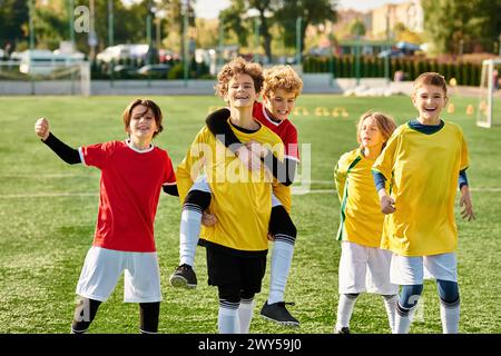 Un groupe de jeunes hommes célèbrent leur victoire en se tenant triomphalement au sommet d’un terrain de football, profitant du moment d’accomplissement et de camaraderie. Banque D'Images