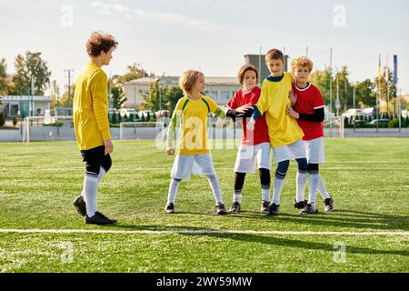 Un groupe dynamique de jeunes enfants se tient triomphalement sur le terrain de football verdoyant, leurs visages rayonnant de joie et d'accomplissement. Le soleil couchant Banque D'Images