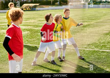 Un groupe joyeux de jeunes enfants se tient triomphalement au sommet d'un terrain de football, unis dans la victoire et la camaraderie après un match. Banque D'Images