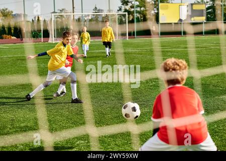 Un groupe dynamique de jeunes enfants jouant énergiquement au soccer sur un terrain herbeux, courant, donnant des coups de pied et acclamant alors qu'ils rivalisent avec eac Banque D'Images