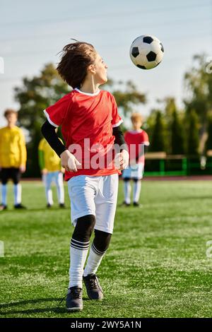 Un jeune garçon plein d'entrain joue énergiquement au football sur un terrain herbeux, dribble habilement devant des adversaires imaginaires avec détermination. Banque D'Images