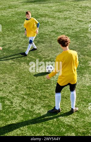 Un groupe animé de jeunes hommes engagés dans un match de football compétitif sur un terrain dynamique. Ils courent, passent et tirent la balle avec énergie Banque D'Images