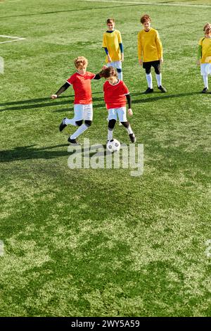 Un groupe de jeunes enfants jouant énergiquement à une partie de football sur un terrain herbeux. Ils courent, dribblent, passent et donnent un coup de pied dans la balle avec en Banque D'Images