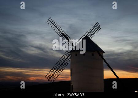 Un grand moulin à vent blanc se dresse contre les montagnes et les nuages Banque D'Images