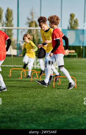 Un groupe de jeunes enfants jouant énergiquement à une partie de football sur un terrain herbeux. Ils courent, frappent le ballon et rient pendant qu'ils rivalisent avec moi Banque D'Images