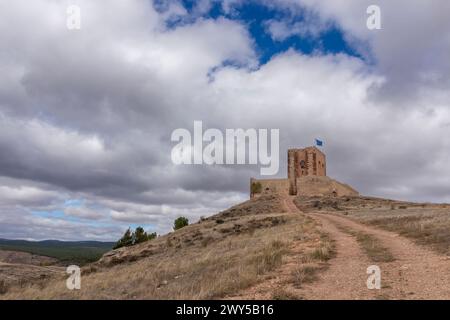 vieille structure en pierre sur une colline, chemin menant vers le haut, drapeau sur le dessus, entouré d'un paysage accidenté et ombragé de nuages Banque D'Images