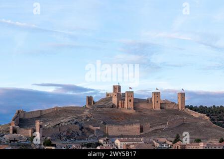 ancien château en pierre avec plusieurs tours surplombe une petite ville, sur fond de ciel nuageux Banque D'Images