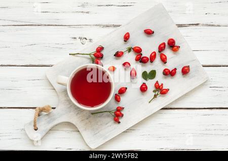 Tasse en verre de rose musquée de plantes médicinales de tisane avec des fruits de rose musquée sur une table rustique. Fond de thé d'hiver Dogrose Banque D'Images