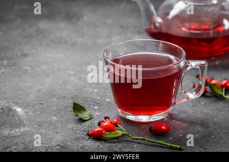 Tasse en verre de rose musquée de plantes médicinales de tisane avec des fruits de rose musquée sur une table rustique. Fond de thé d'hiver Dogrose Banque D'Images