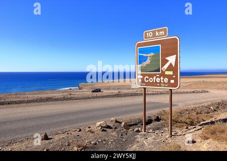 19 novembre 2023 - Morro Jable, Jandia, Fuerteventura en Espagne : route de gravier, poussiéreuse avec de hautes montagnes volcaniques en arrière-plan Banque D'Images