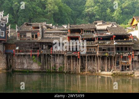 Les vieux bâtiments en bois sur le bord de la rivière à Fenghuang, une ancienne ville de Hunan, en Chine. Quelques presque 400 ans et a soutenu avec des stilts. Banque D'Images