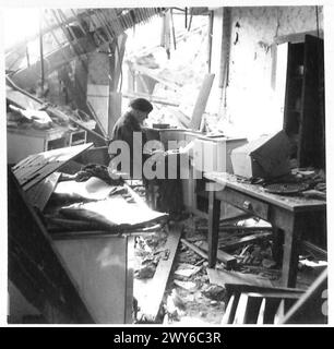 James McDonald, correspondant de guerre de New York, dresse des dépêches en Allemagne à partir des ruines d'une maison. Armée britannique, 21e groupe d'armées présent. Banque D'Images
