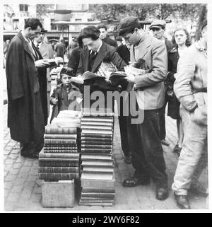 MARCHÉ DU DIMANCHE MATIN À BRUXELLES - cette série de photographies prises à Bruxelles illustre un marché typique du dimanche matin. Il est très semblable à notre Petticoat Lane où l'on peut acheter presque n'importe quoi. Des foules de folkloriques belges parcourent le marché à la recherche d'articles tels que des livres, du matériel, des pièces de vélo, des fruits et de nombreux autres articles dont ils ont besoin. Dans cette série est une vue générale d'une rue où le marché noir de Bruxelles s'est déroulé. Pas le marché noir comme nous le comprenons, mais où les Belges étaient approvisionnés en nourriture, etc., qui était interdit par les Allemands. [CES PHOTOGRAPHIES SONT À ILLUST Banque D'Images