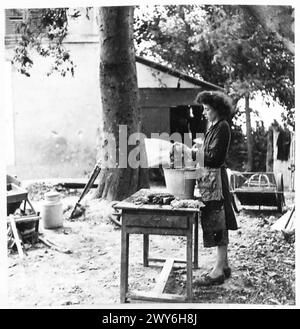 Une FAMILLE FRANÇAISE RETOURNE DANS LEUR VILLAGE DÉCHIRÉ DE COQUILLAGES - les vêtements de la famille sont sales alors mari-Anne procède à faire un peu de lavage dans le jardin. , Armée britannique, 21e groupe d'armées Banque D'Images