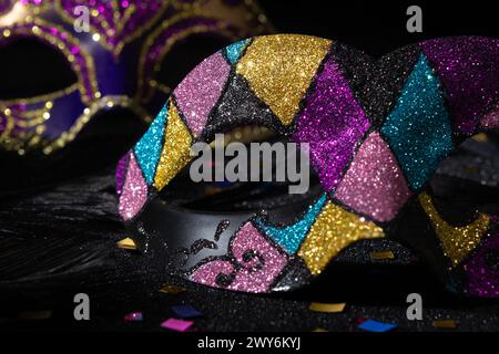 Masque de mascarade avec des paillettes et confetties sur fond noir. Banque D'Images