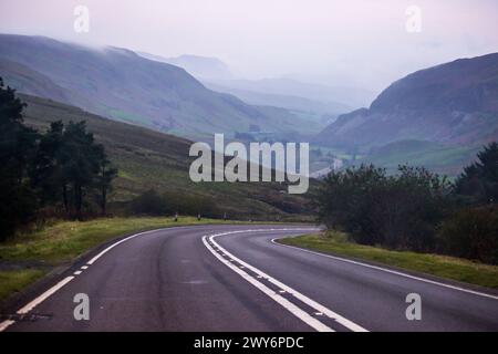 Route descendant dans une mystérieuse vallée brumeuse dans le parc national d'Eryri au pays de Galles Banque D'Images