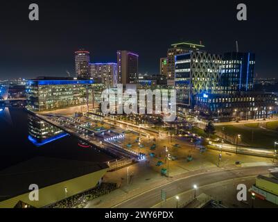 Photographie nocturne par drone à MediaCityUK, Salford Quays, y compris les BBC Studios, l'Université de Salford et le Dock 10 au premier plan Banque D'Images