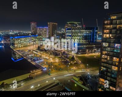 Photographie nocturne par drone à MediaCityUK, Salford Quays, y compris les BBC Studios, l'Université de Salford et le Dock 10 au premier plan Banque D'Images