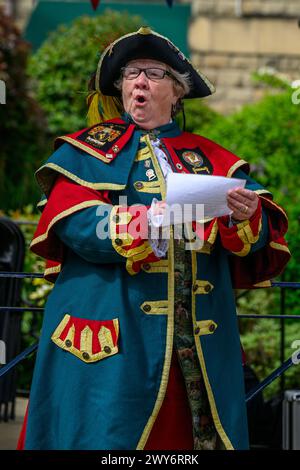 Crier de ville féminine (uniforme de crieur tressé coloré) proclamant, faisant une proclamation publique forte et annonce - Ilkley, West Yorkshire Angleterre Royaume-Uni. Banque D'Images