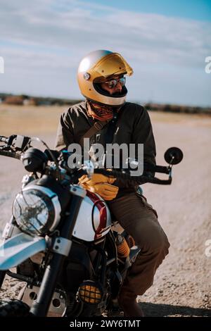 L'homme en casque est assis sur la moto dans le désert Banque D'Images