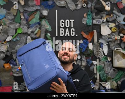 Mainz, Allemagne. 04th Apr, 2024. Benjamin Mandos, fondateur de la société Got Bag, basée à Mayence, se tient devant un mur avec un sac à dos sur lequel des déchets plastiques ont été collés autour du logo de la marque. Fondée en 2016, la start-up utilise pour ses sacs à dos et valises des tissus fabriqués à partir de plastique recyclé provenant de la mer ou de la mangrove, connu sous le nom de plastique Ocean impact. Crédit : Arne Dedert/dpa/Alamy Live News Banque D'Images