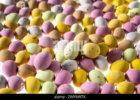 Mini oeufs en chocolat enrobés de sucre de couleur pastel sur fond blanc Banque D'Images