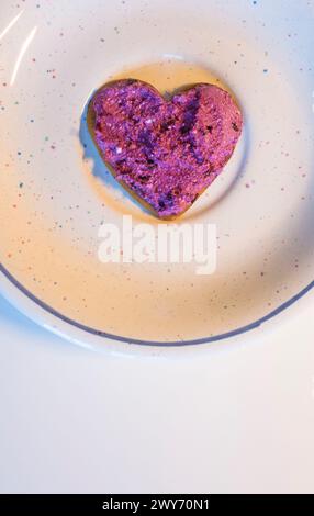 Tartiner en forme de coeur avec crème de caillé de myrtille pour la Saint-Valentin sur l'assiette sur la vue de dessus de table blanche, photo verticale avec espace pour le texte Banque D'Images