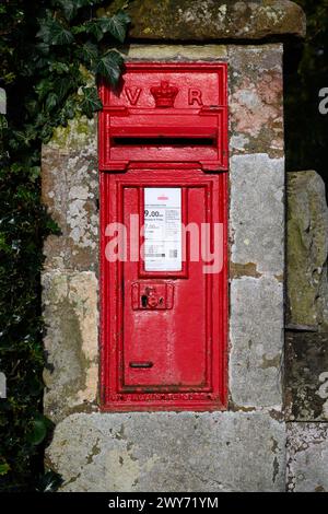 Shawbury, Royaume-Uni - 18 mars 2024 ; boîte postale anglaise rouge dans le mur avec lettres de la reine Victoria Banque D'Images