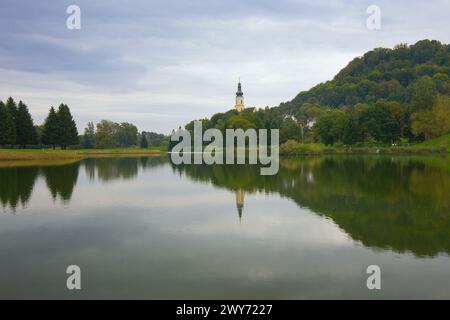 Vue sur le lac de baignade jusqu'à l'église paroissiale catholique de équipé Magdalena à Wildon, Autriche. Banque D'Images