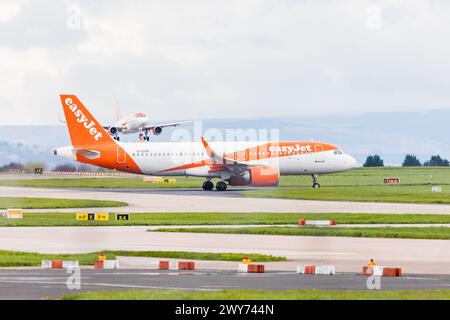 Deux Airbus A320 EasyJet photographiés à l'aéroport de Manchester le 4 avril 2024, l'un circulant pour le décollage et l'autre se préparant à atterrir. Banque D'Images