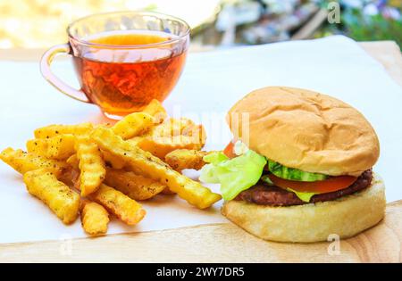 Délicieux burger de bœuf maison avec champignons, micro légumes verts, oignon rouge, sauce betterave sur planche de bois. Vue latérale de la tasse à thé, gros plan. Banque D'Images