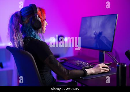 Focused Gamer jouant au jeu de tir à la première personne dans une salle vibrante et colorée Banque D'Images