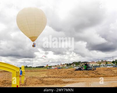 Montgolfière volant dans le ciel au-dessus de la campagne lors d'un événement de loisirs avec quatre par quatre et paramoteur. Banque D'Images