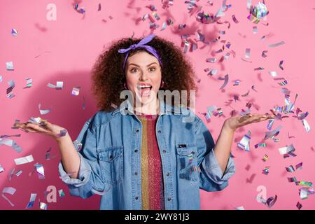 Photo de joyeuse tenue de jeans habillée de dame impressionnée attrapant des confettis volants de fond de couleur rose isolé Banque D'Images