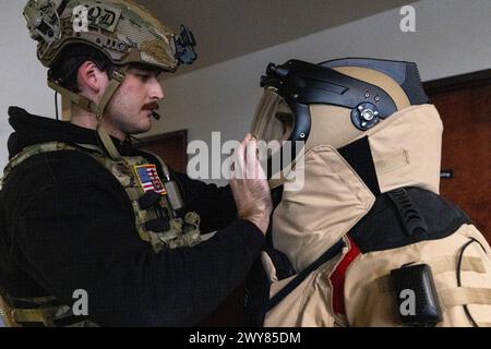 27 mars 2024 - Trenton, New Jersey, États-Unis - Air Force Airman 1st Class Robert Wittig, à gauche, ferme le casque sur l'aviateur senior Russell J. Bongiovanni's EOD-10E Bomb combinaison, tous deux techniciens d'élimination de munitions explosives avec la 177th Fighter Wing, New Jersey Air National Guard, pendant le joint Chemical, Biological, le cours de caractérisation, d'exploitation et d'atténuation des explosifs radiologiques, nucléaires et à haut rendement JCCEM à la CURE Insurance Arena avec le FBI, la police d'État du New Jersey et les membres des WMD-CST du Delaware et de l'Idaho ont été formés par l'Eniwetok Group, LLC (EGL). (Crédit image : © Banque D'Images