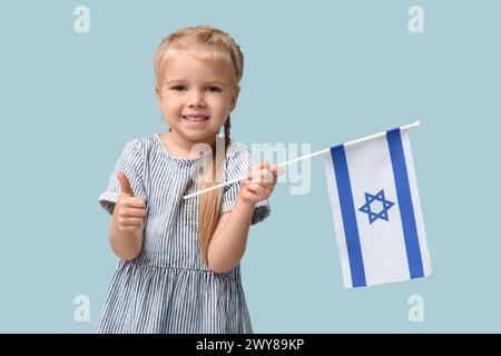 Jolie petite fille heureuse avec le drapeau d'Israël sur fond bleu. Célébration Hanukkah Banque D'Images