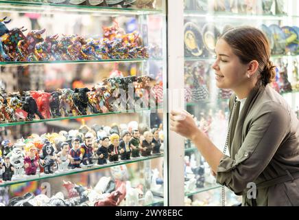 La jeune femme choisit la figurine au marché de souvenirs Banque D'Images