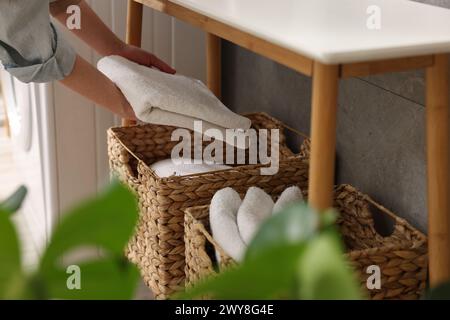 Femme mettant la serviette dans le panier de rangement à l'intérieur, gros plan Banque D'Images