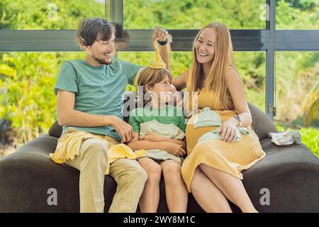 Moment de famille réconfortant alors que maman, papa et fils passent joyeusement à travers les vêtements du nouveau-né, anticipant avec impatience l'arrivée d'un nouveau-né Banque D'Images