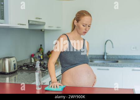 Une femme enceinte fatiguée est assise dans la cuisine après le nettoyage. Santé et vitalité d'une femme enceinte Banque D'Images